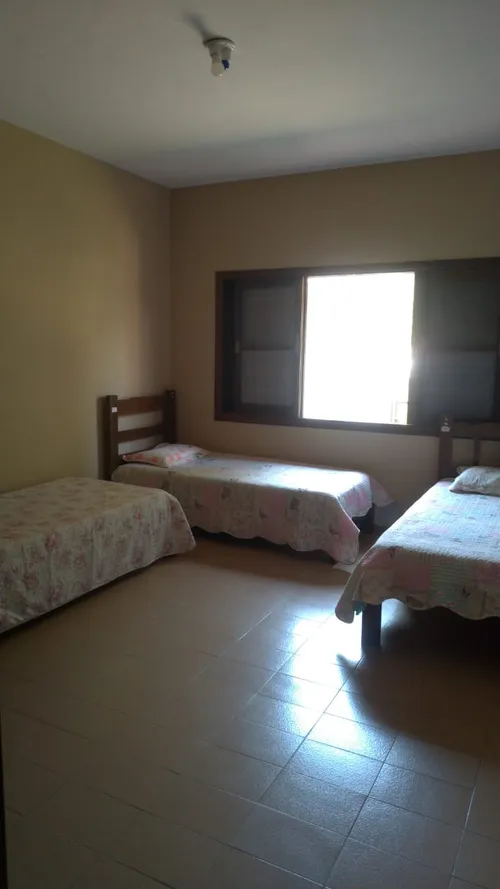 Quarto triplo arejado com três camas e janela ampla